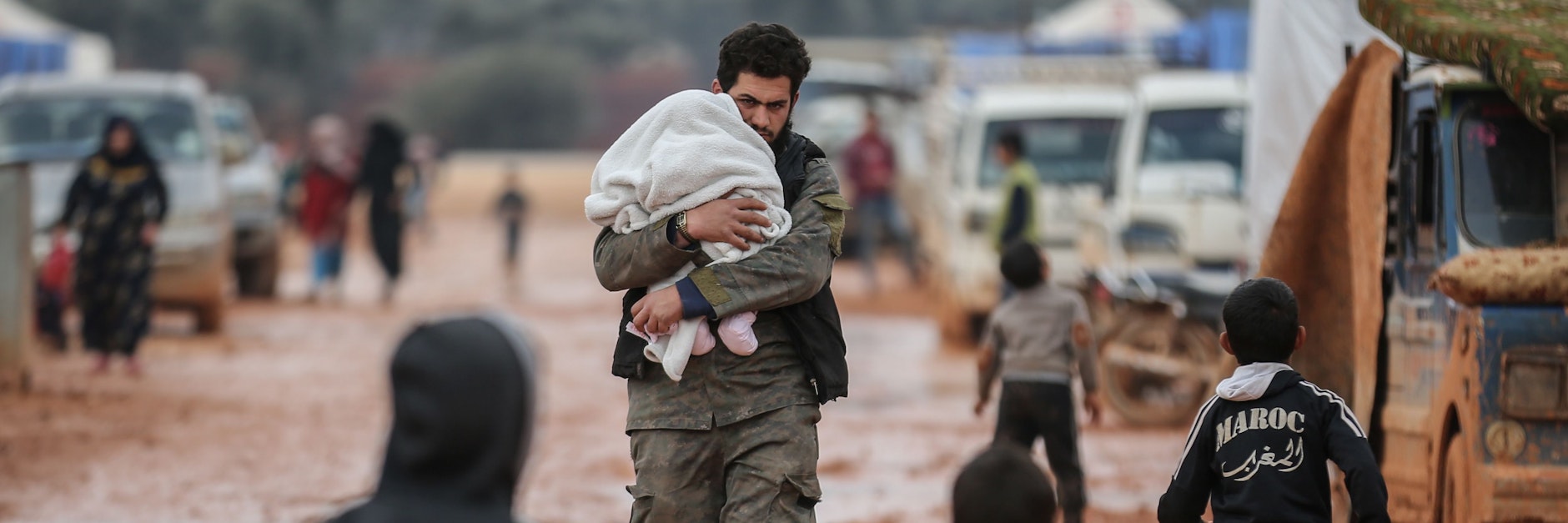 In einem syrischen Behelfslager für Opfer von Bombenangriffen trägt ein Mann sein Kind. Syrien ist weiter eines der Länder, in dem Nothilfe am meisten nötig ist.