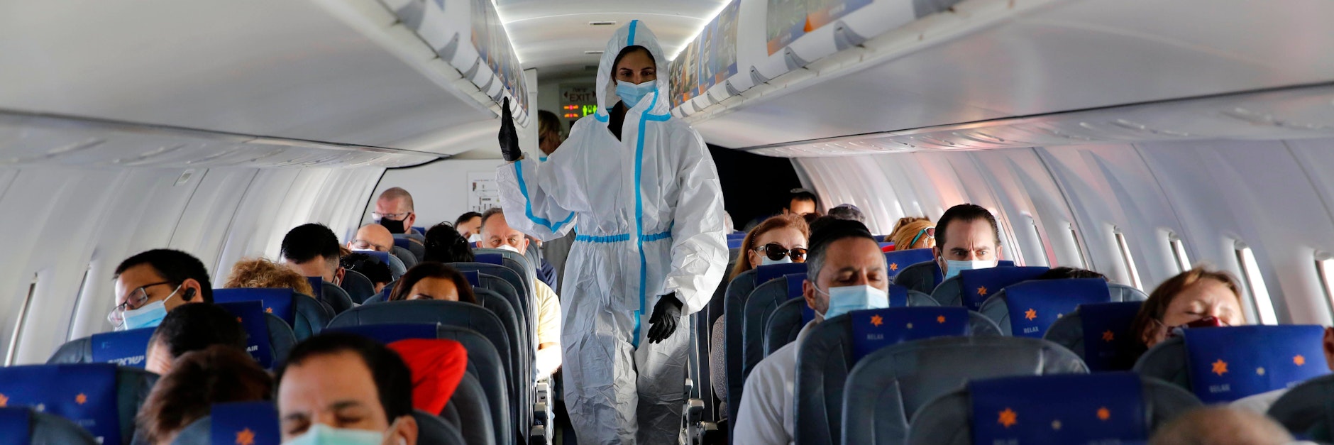 Eine israelische Flugbegleiterin trägt Maske und einen Ganzkörperschutzanzug.