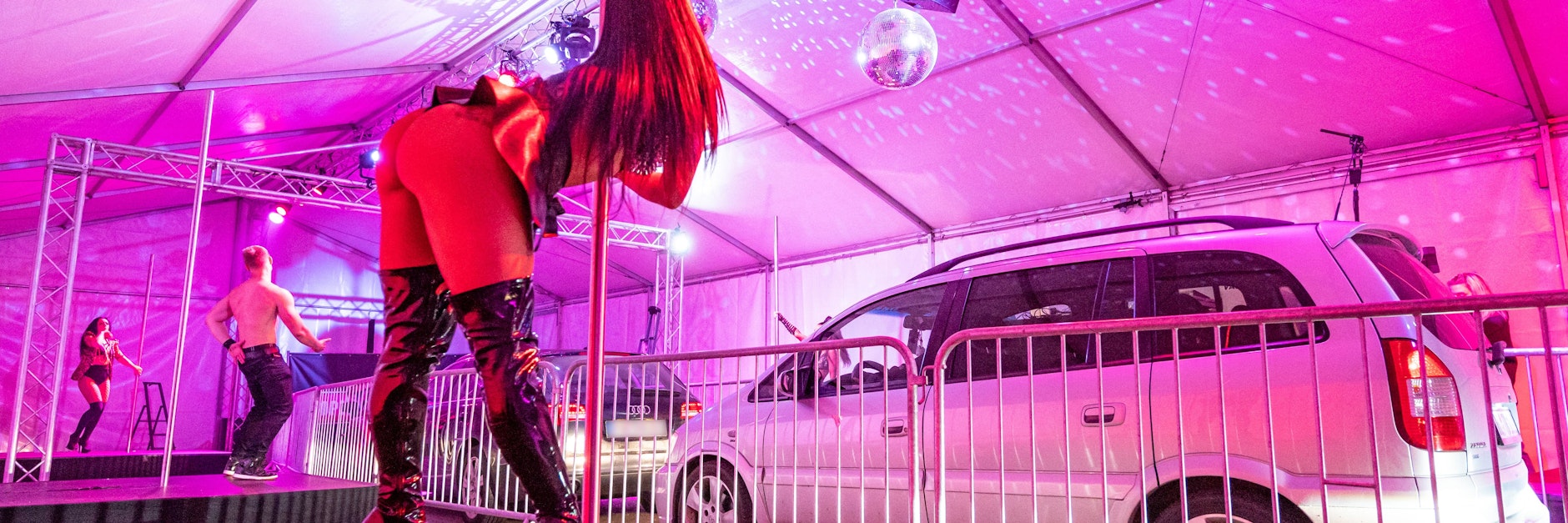 Tänzerinnen und Tänzer in Landshut stehen im Strip-Drive-in auf Bühnen vor Autos. In dem Zelt können die Fahrzeuginsassen die Stripperinnen und Stripper im vorgeschriebenen Mindestabstand bewundern.