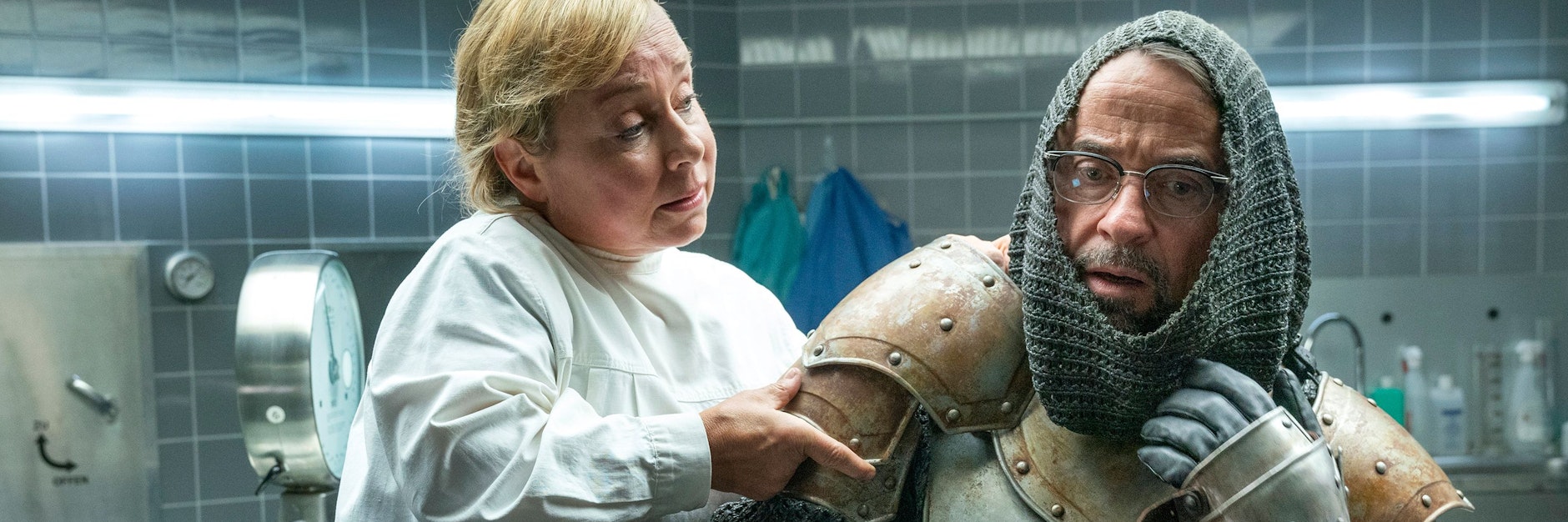 Anprobe in der Rechtsmedizin: Silke Haller (ChrisTine Urspruch) hilft Prof. Karl-Friedrich Boerne (Jan Josef Liefers) dabei, die Ritterrüstung anzulegen - eine Szene aus „Tatort: Es lebe der König!“