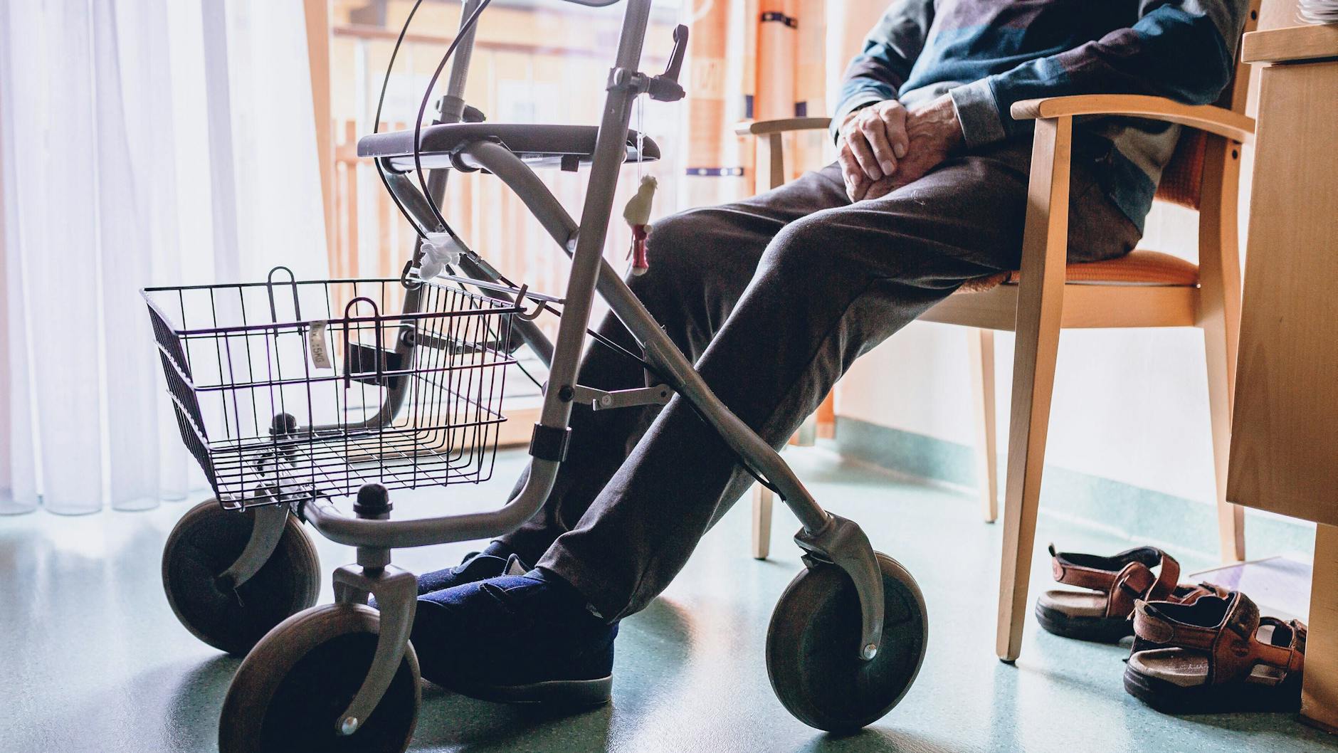 Ein alter Mann sitzt in einem Pflegeheim auf einem Stuhl (Symbolbild)