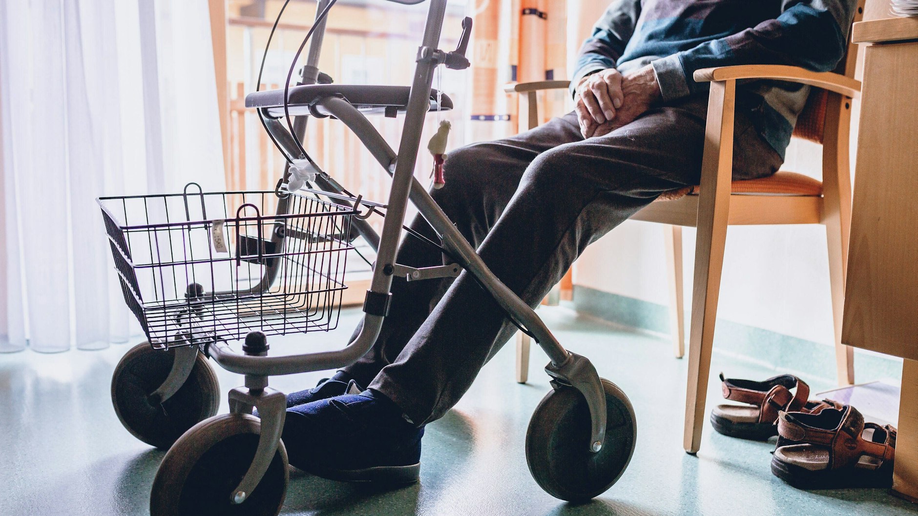 Ein alter Mann sitzt in einem Pflegeheim auf einem Stuhl (Symbolbild)