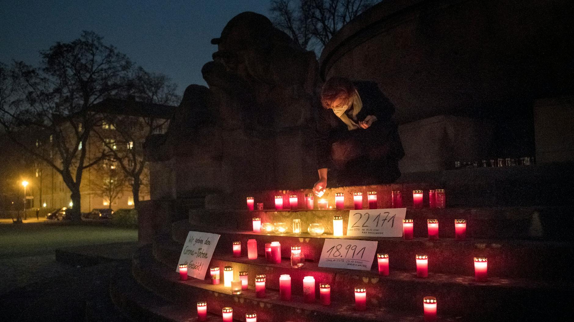 Eine Passantin zündet auf dem Arnswalder Platz eine Kerze in Gedenken an die an Corona verstorbenen Menschen an.<br>