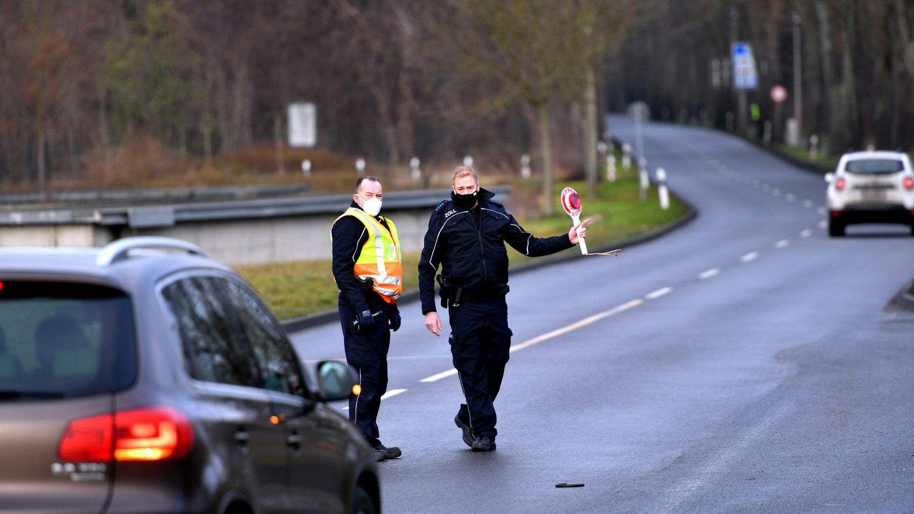 Zwei deutsche Grenzkontrolleure halten mit einem Warnlicht ein Auto am Grenzübergang zu Deutschland in Krajnik Dolny im Nordwesten Polens an.
