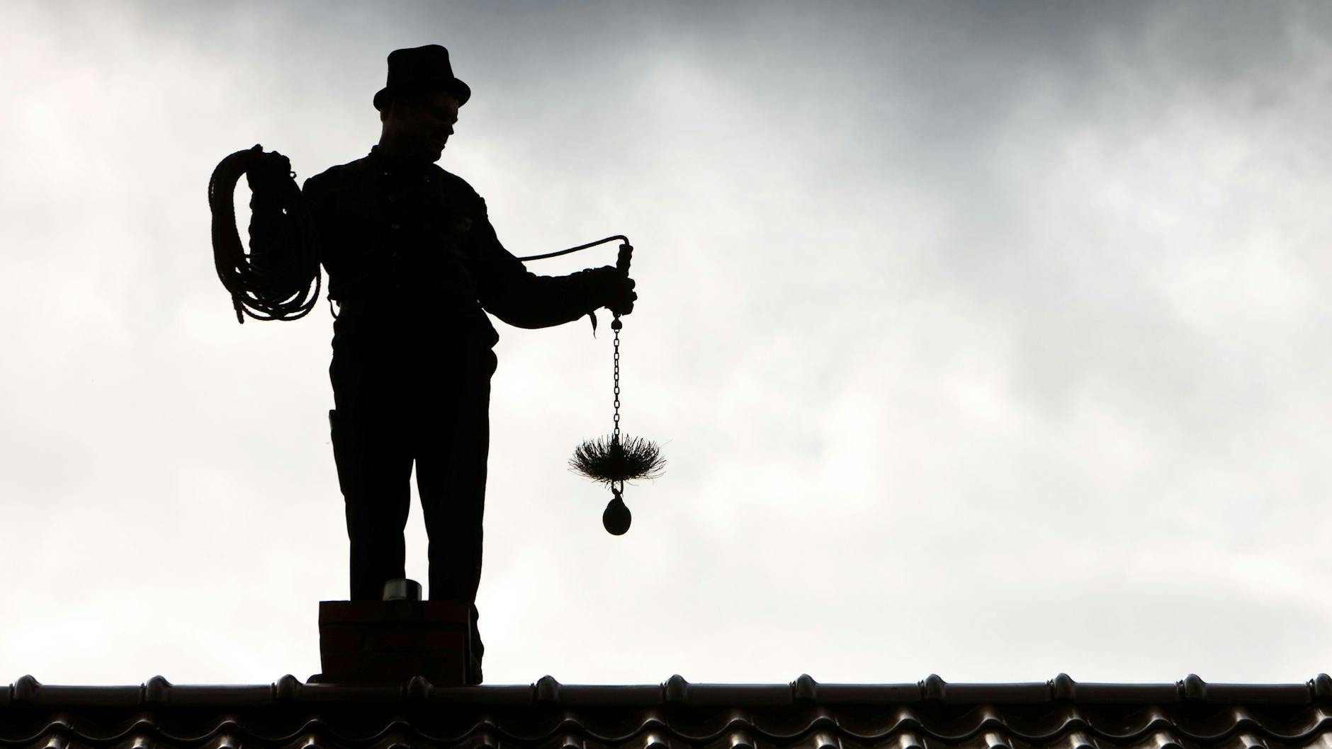 Von Seltenheitswert: Ein Schornsteinfeger mit Zylinder und Kehrgerät.