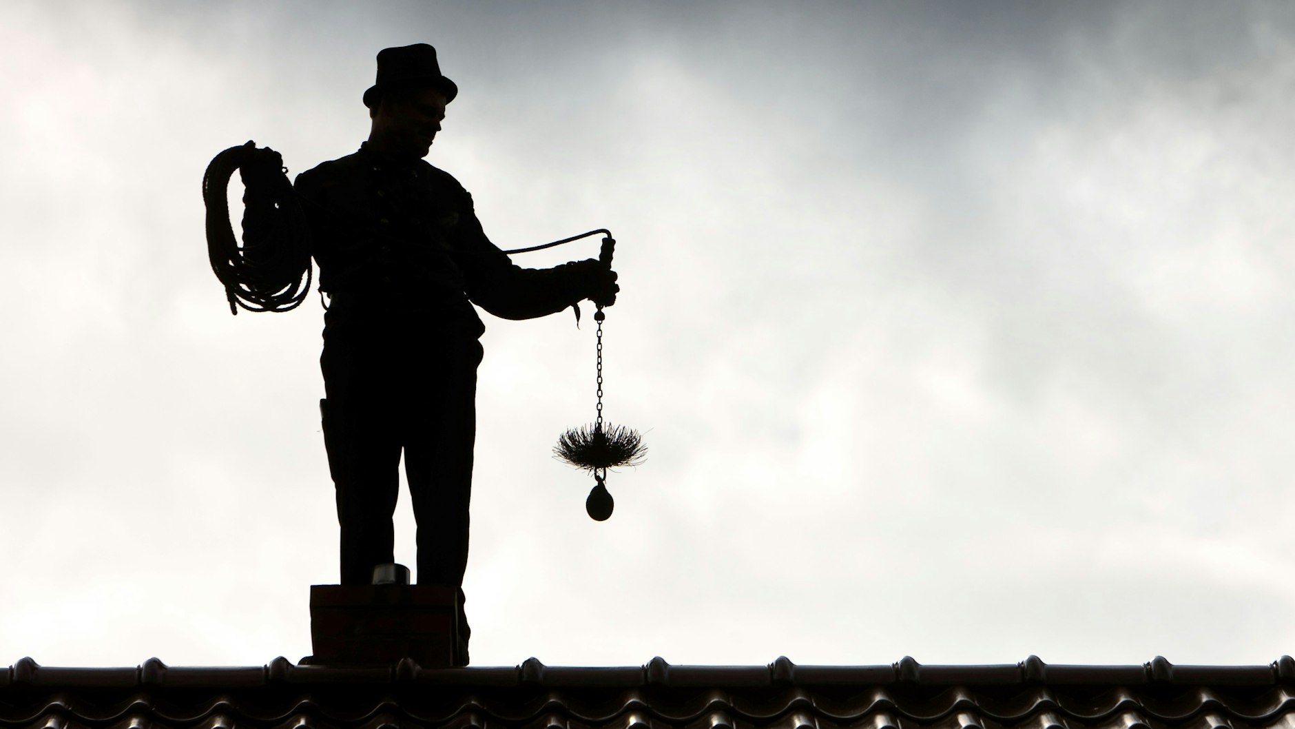 Von Seltenheitswert: Ein Schornsteinfeger mit Zylinder und Kehrgerät.