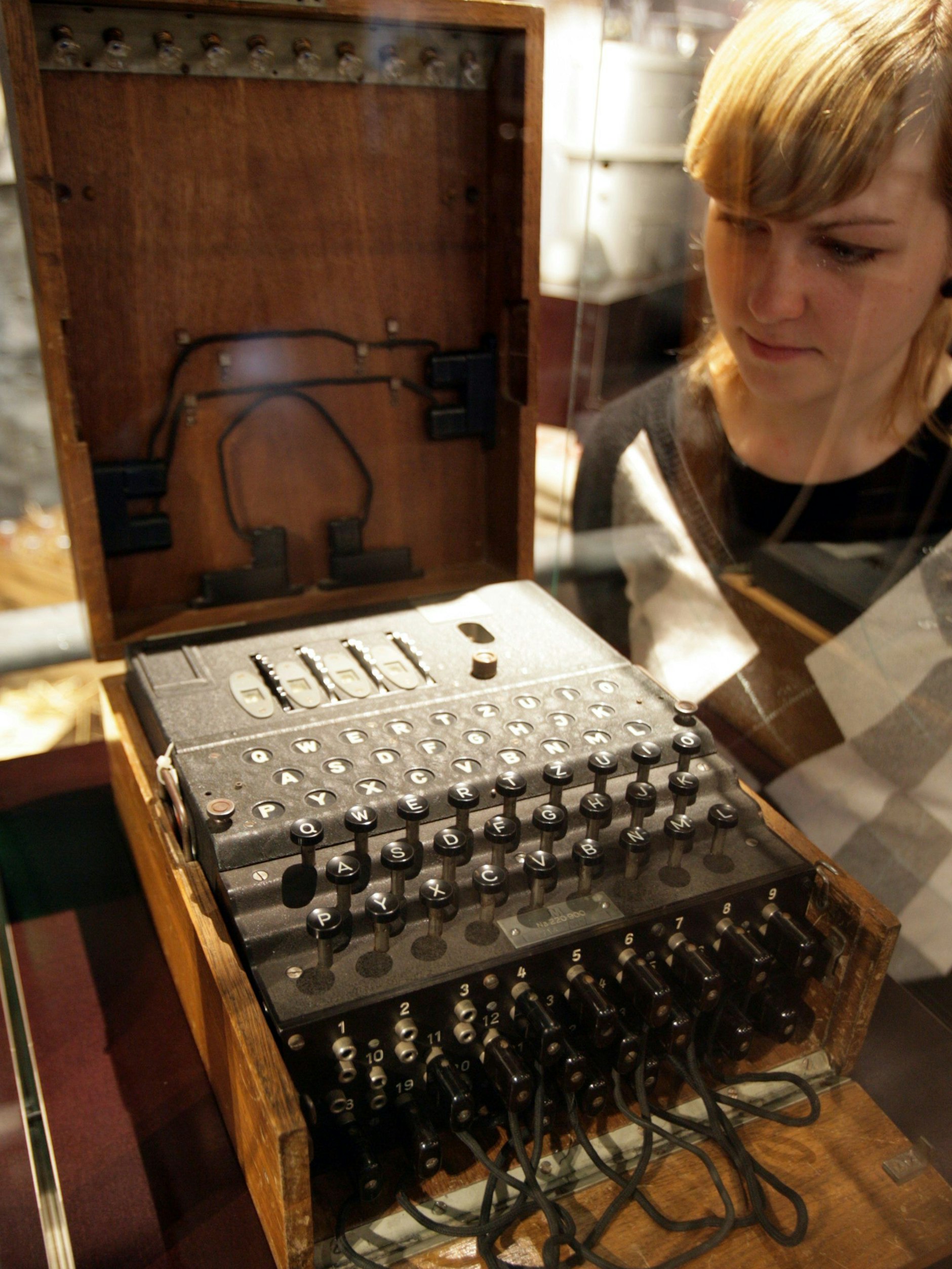 Eine Mitarbeiterin des Hauses der Geschichte der Bundesrepublik Deutschland in Bonn betrachtet eine Rotor-Chiffriermaschine Enigma der deutschen Wehrmacht aus der Zeit des Zweiten Weltkriegs