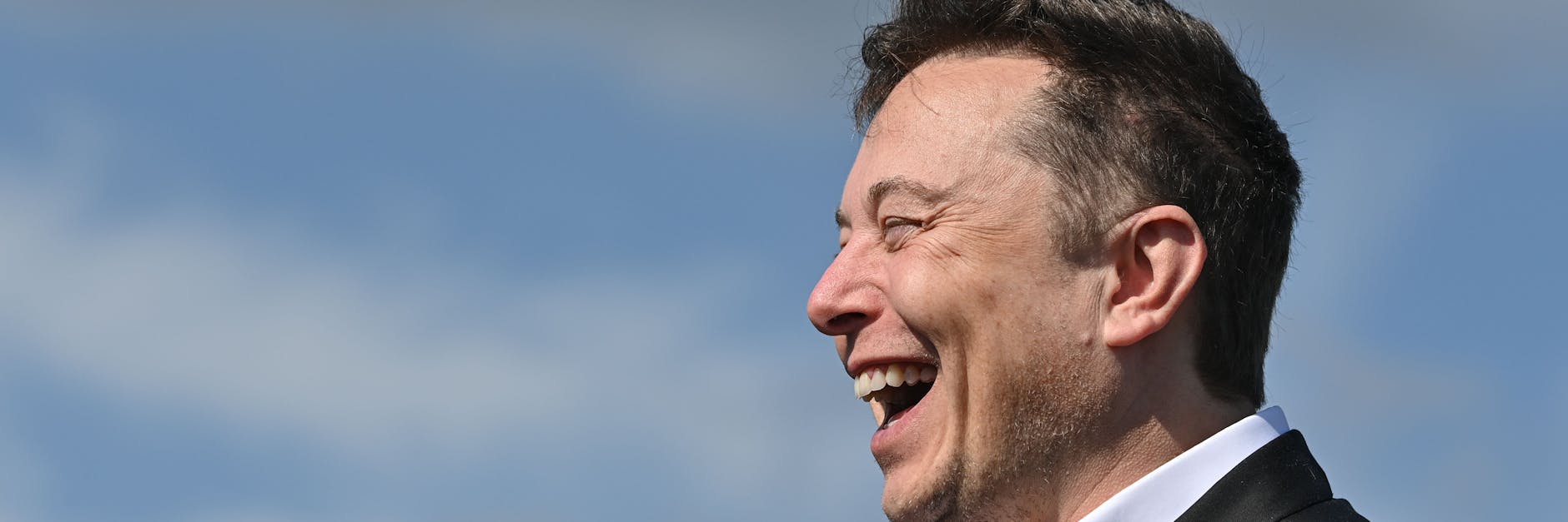 Elon Musk, Tesla-Chef, steht lachend auf der Baustelle der Tesla Gigafactory.