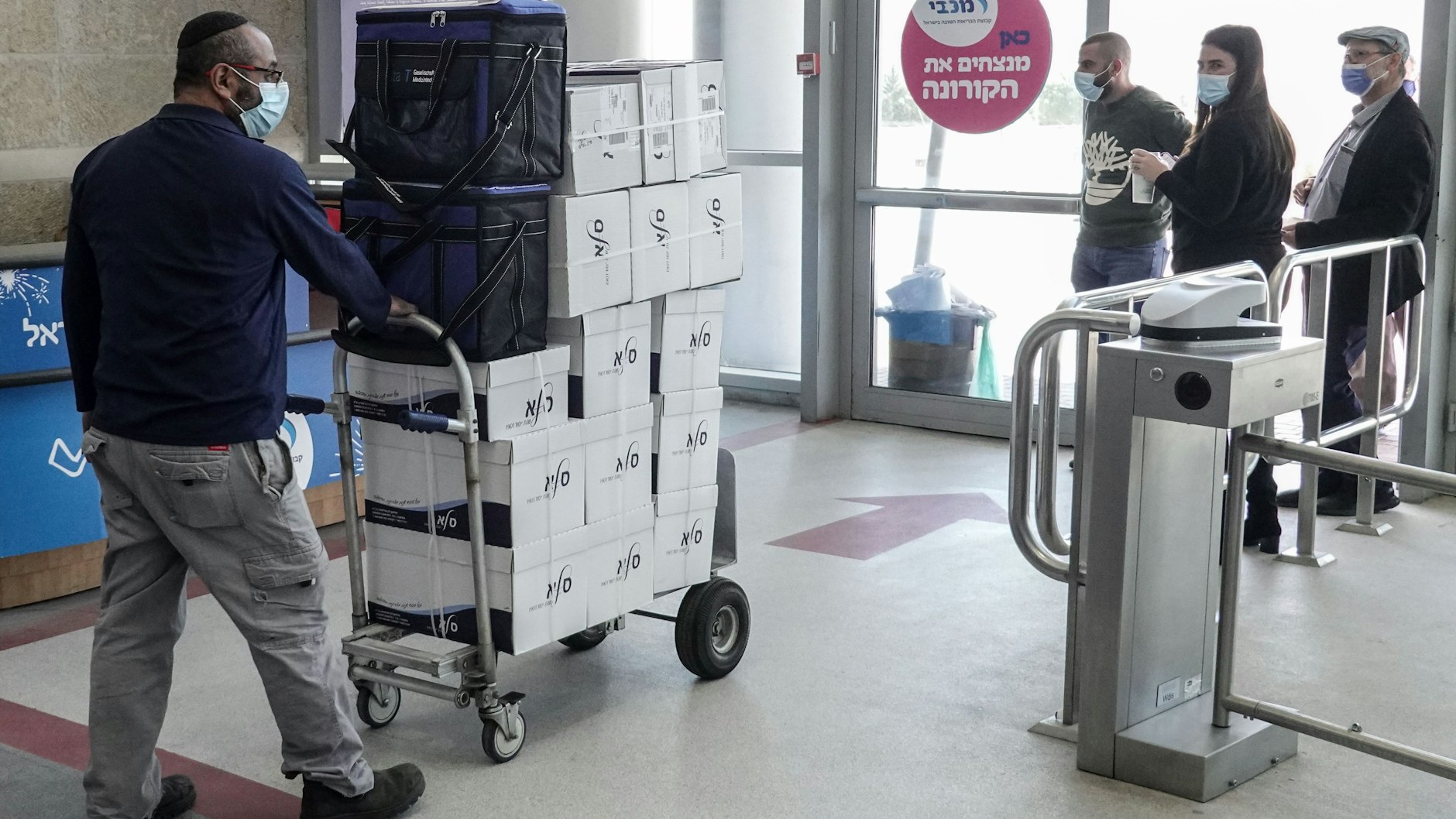 Eine Person mit Mund-Nasen-Schutz bringt Kartons mit dem Corona-Impfstoff von Pfizer-Biontech in ein israelisches Impfzentrum.