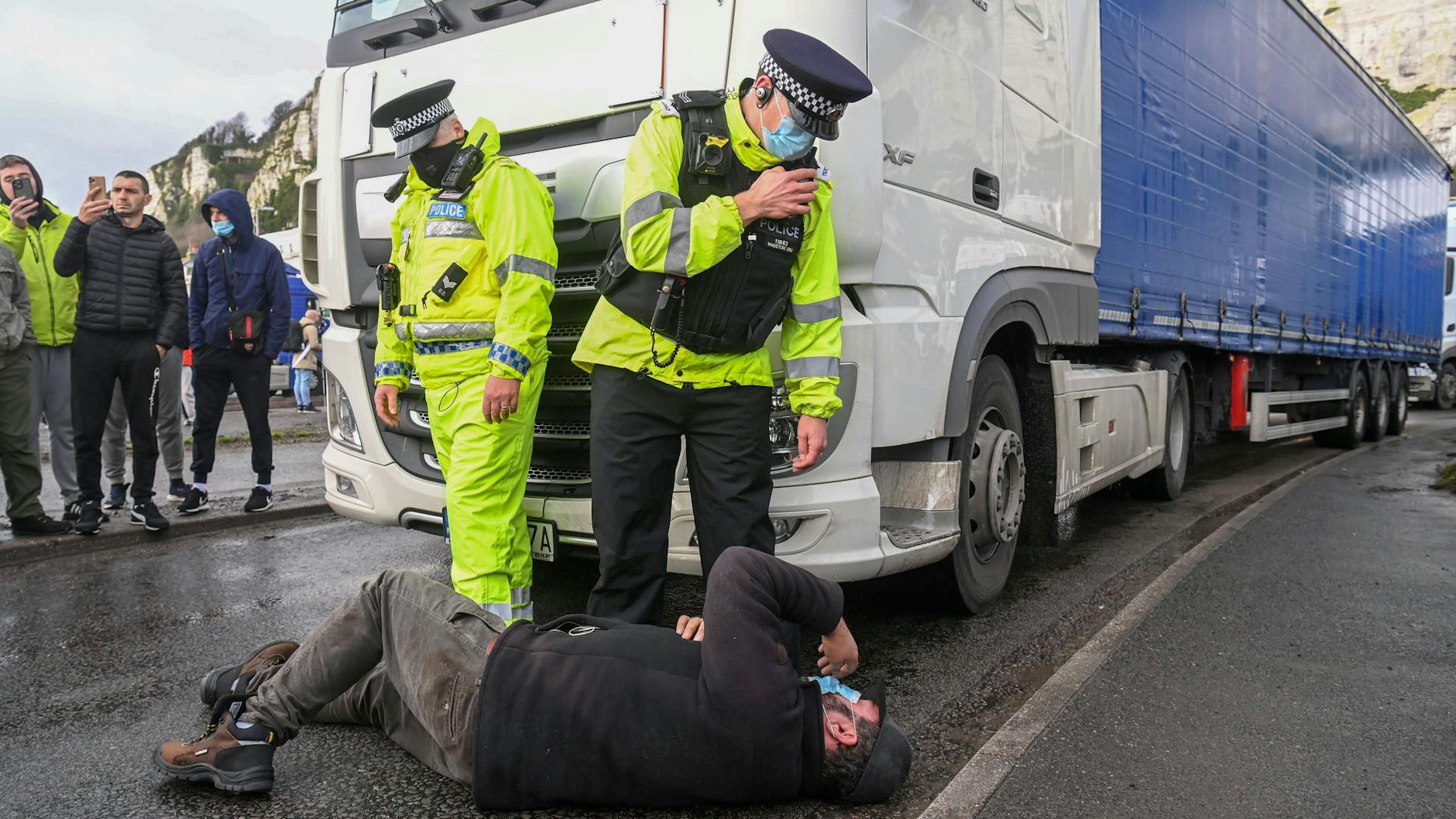 LKW-Fahrer protestieren gegen die Grenzsperrung. Dieser Mann wirft sich vor Grenzbeamten an der britischen Hafenstadt Dover auf den Boden.