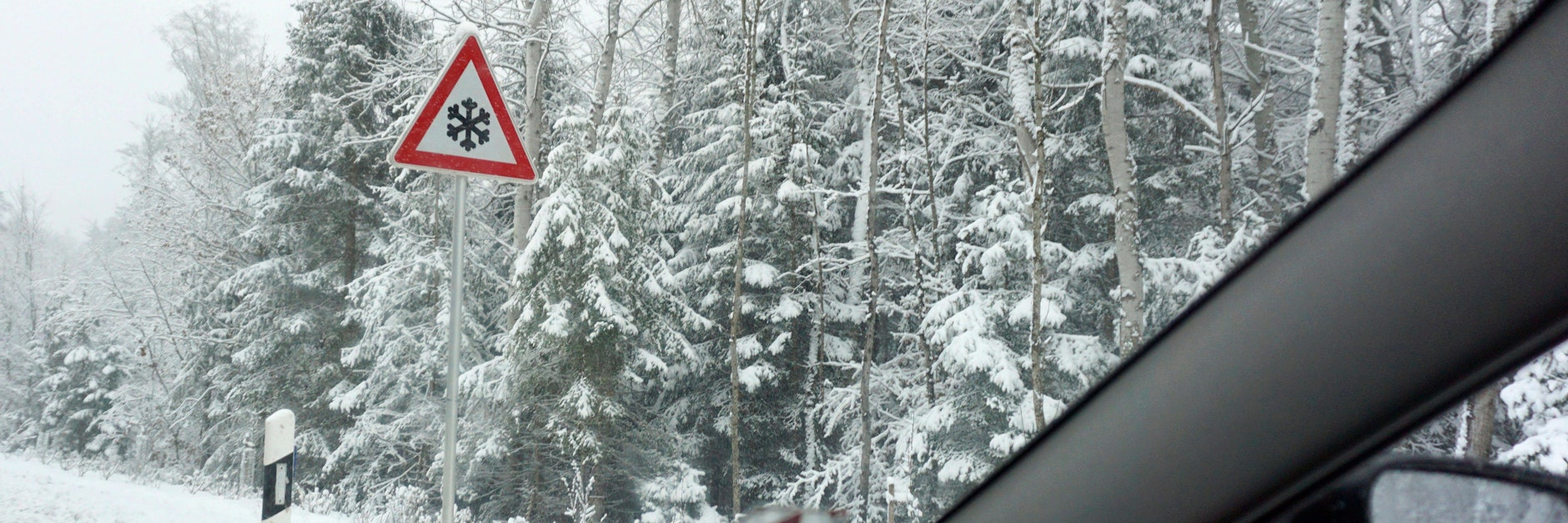 Eine verschneite Straße vom Auto aus aufgenommen (Symbolfoto).
