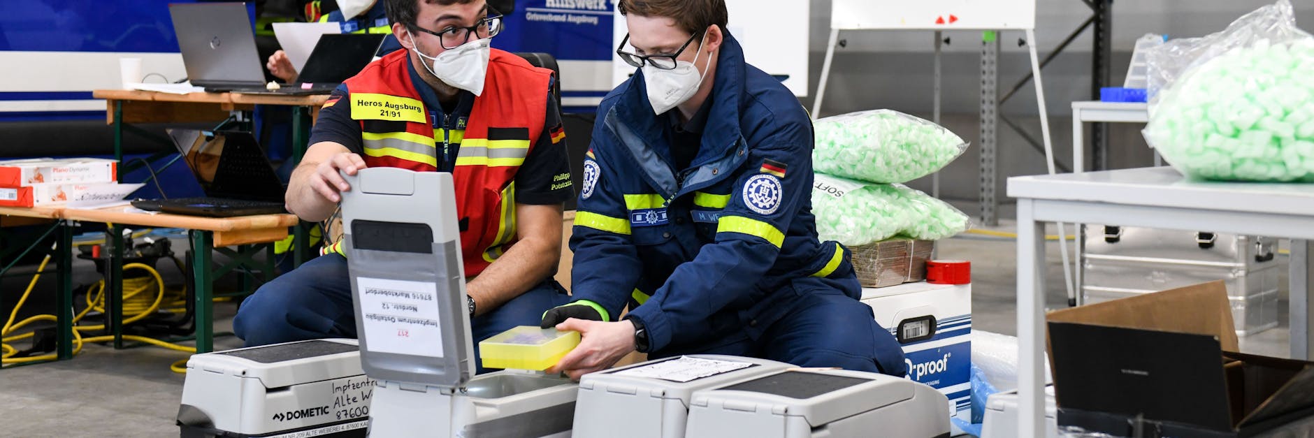Mitarbeiter des Technischen Hilfswerks legen Impfstoff-Fläschchen in eine Spezial-Transportbox.
