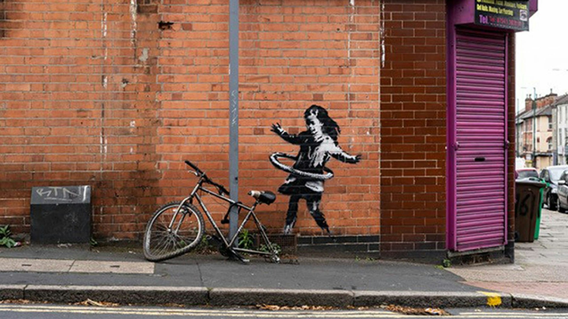 Dieses Werk von Banksy in Nottingham zeigt ein Mädchen, das mit einem Fahrradreifen Hula Hoop spielt. Dem realen Rad davor fehlt ein Reifen.