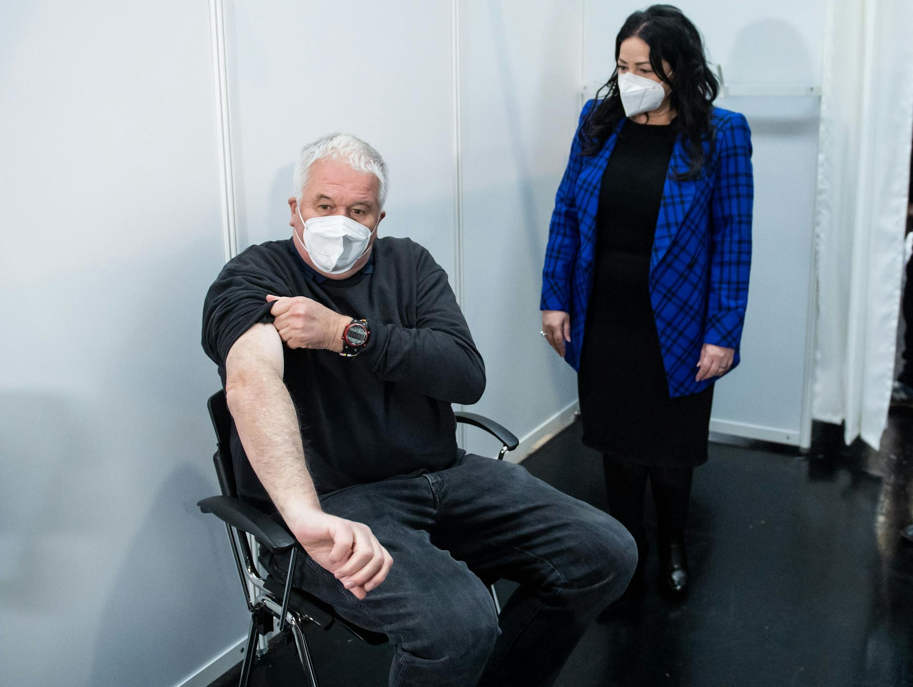 Albrecht Broemme demonstriert Gesundheitssenatorin Dilek Kalayci den Ablauf in der Impfkabine. Jacke ausziehen, Ärmel hochkrempeln, Spritze bekommen, wieder gehen - länger als zehn Minuten dauert das alles nicht.