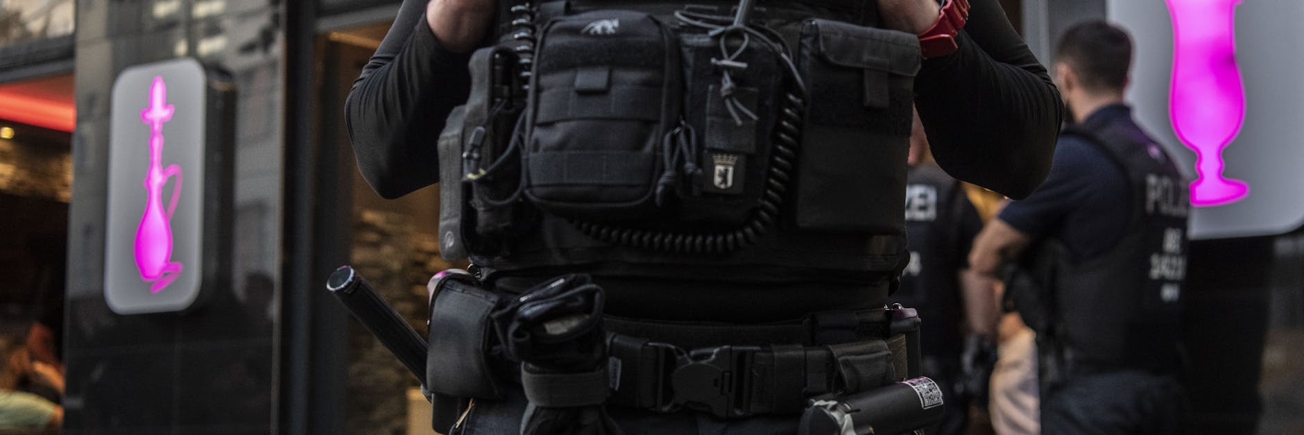 Polizeibeamte stehen bei einer Großrazzia in Neukölln vor einem Lokal.