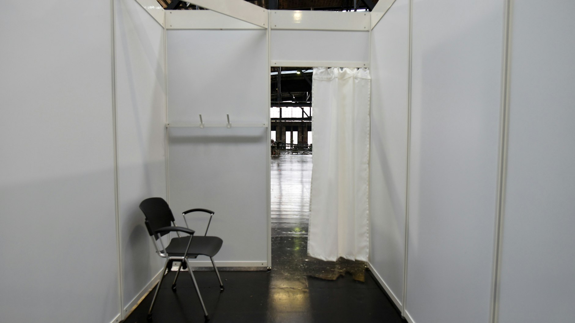 Ganz schlicht gehalten: Ein Stuhl, zwei Haken für Jacke und Mantel - so sieht die Impfkabine aus.