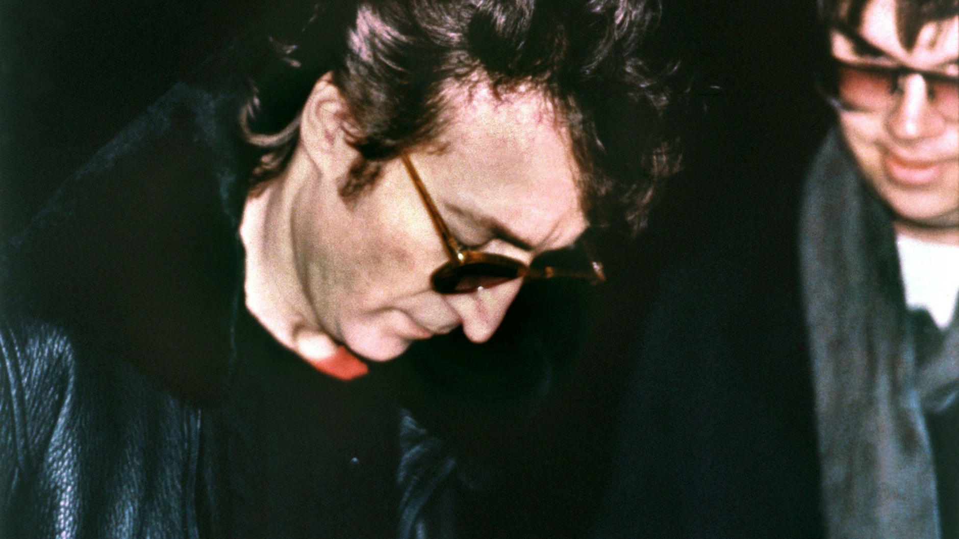 Ein Fotograf hält die Szene durch Zufall fest, wie John Lennon seinem späteren Mörder Mark David Chapman (re.) ein Autogramm gibt.