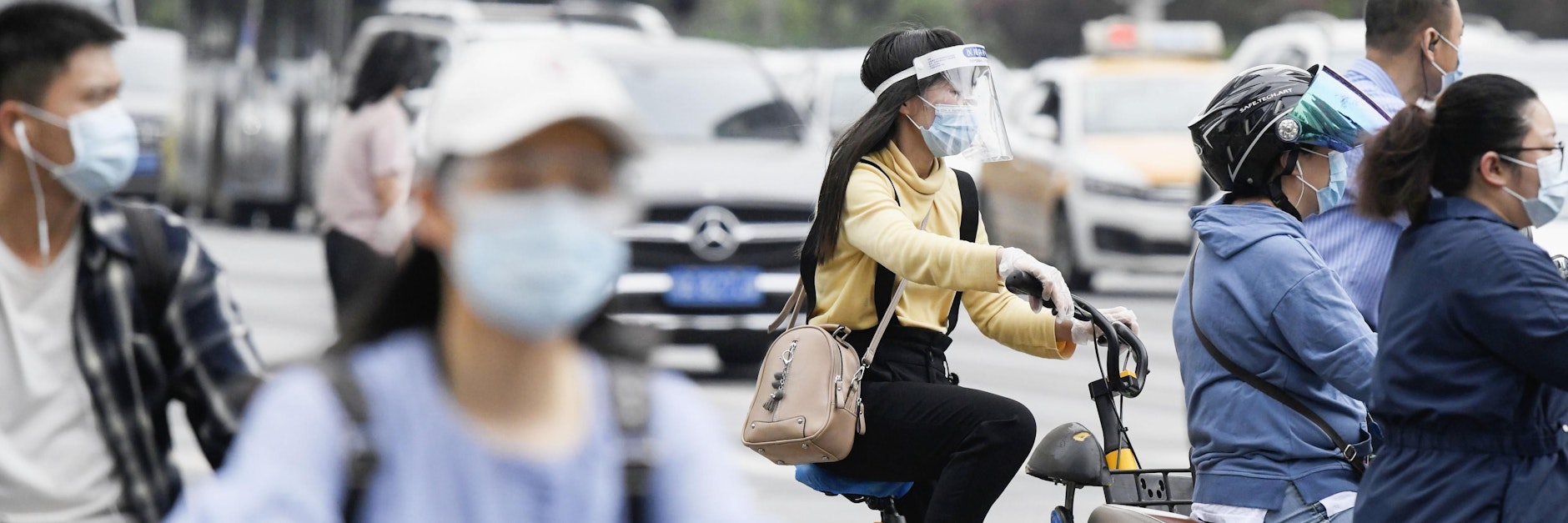 Pendler fahren in Wuhan mit Mund-Nasen-Scutz und Gesichtsschutz auf Motorrädern und Fahrrädern zur Arbeit. Gut ein Jahr nach dem Ausbruch gilt das Coronavirus in China als so gut wie besiegt.&nbsp;