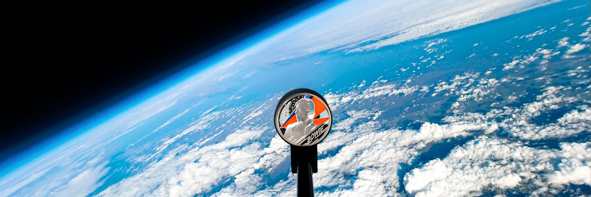 Das Bild zeigt eine Gedenkmünze zu Ehren der britischen Pop-Ikone David Bowie, die im Weltall zu sehen ist.