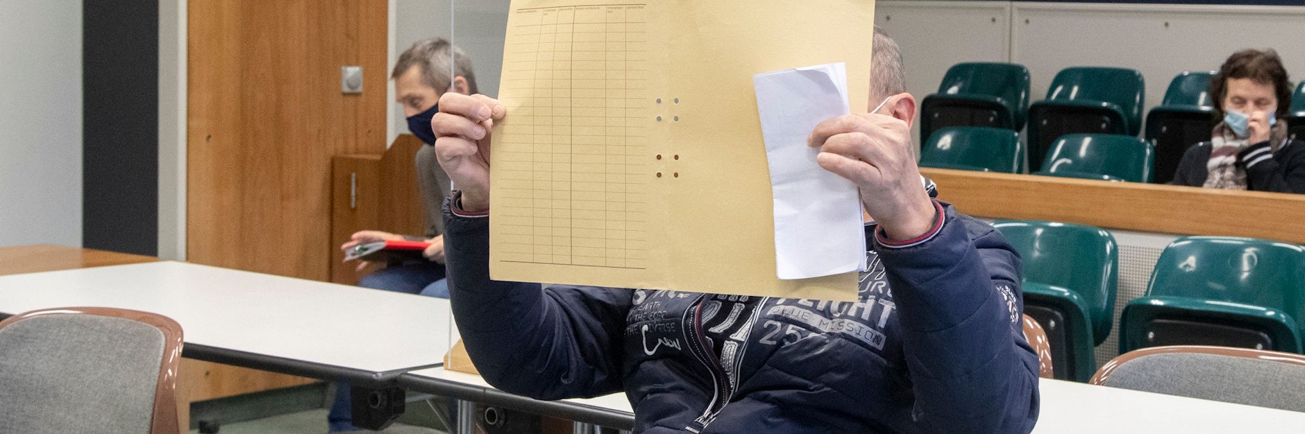 Der Angeklagte Mario G. sitzt im Gerichtssaal und verdeckt sein Gesicht.