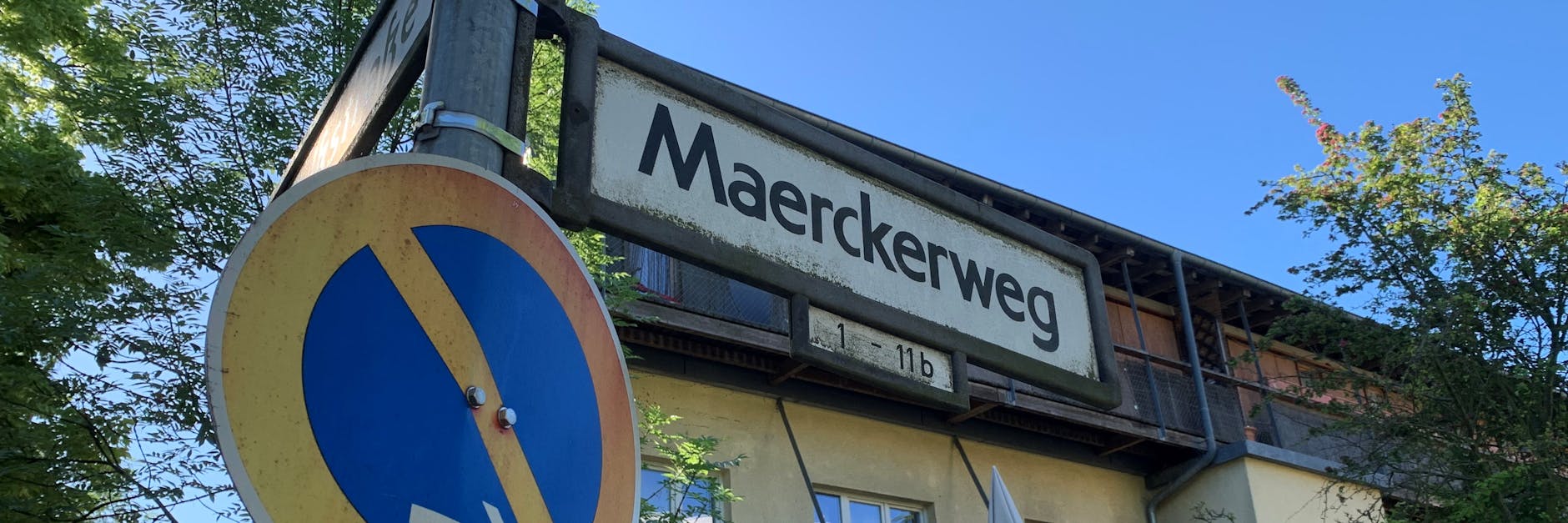 Ein etwas bemoostes Straßenschild des Maerckerwegs, der etwa 150 Meter lang ist und nur die Nummern 1 bis 11b hat. 