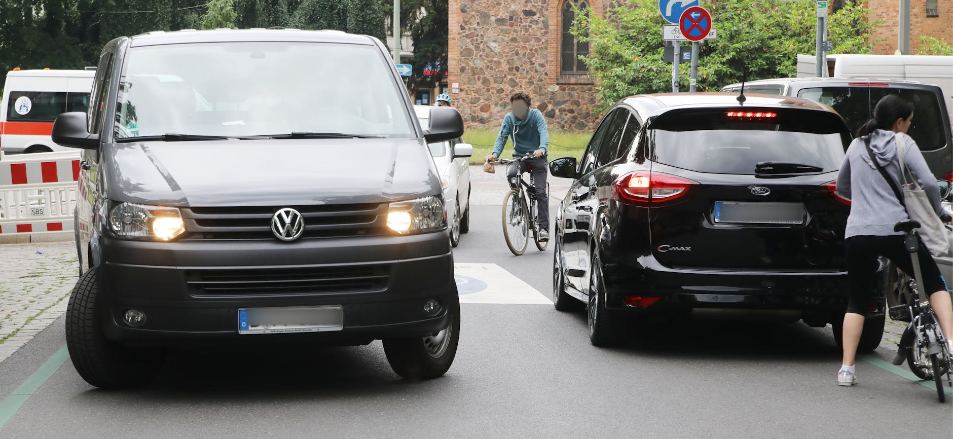 Radfahrer schlängeln sich durch fahrende Autos. 
