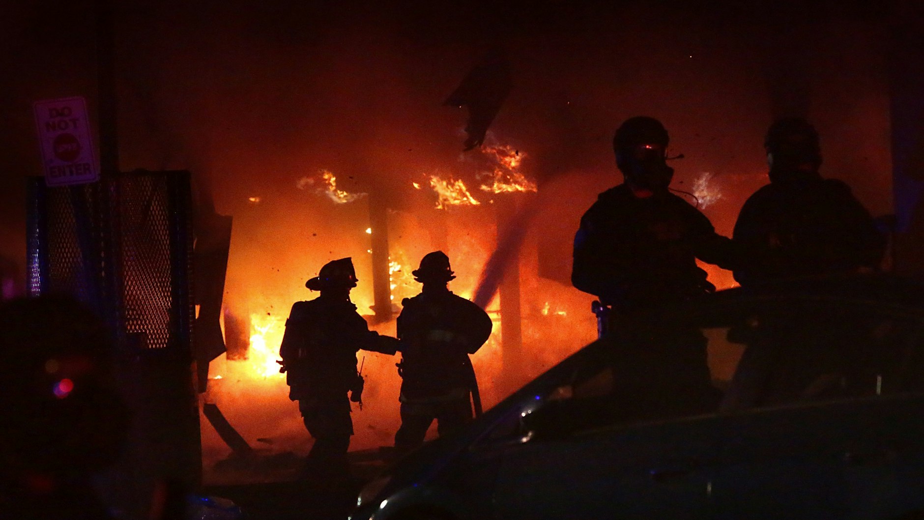 Geschützt von Polizisten, löschen Feuerwehrleute einen Brand im geplünderten 7-Eleven-Markt in St. Louis.&nbsp;