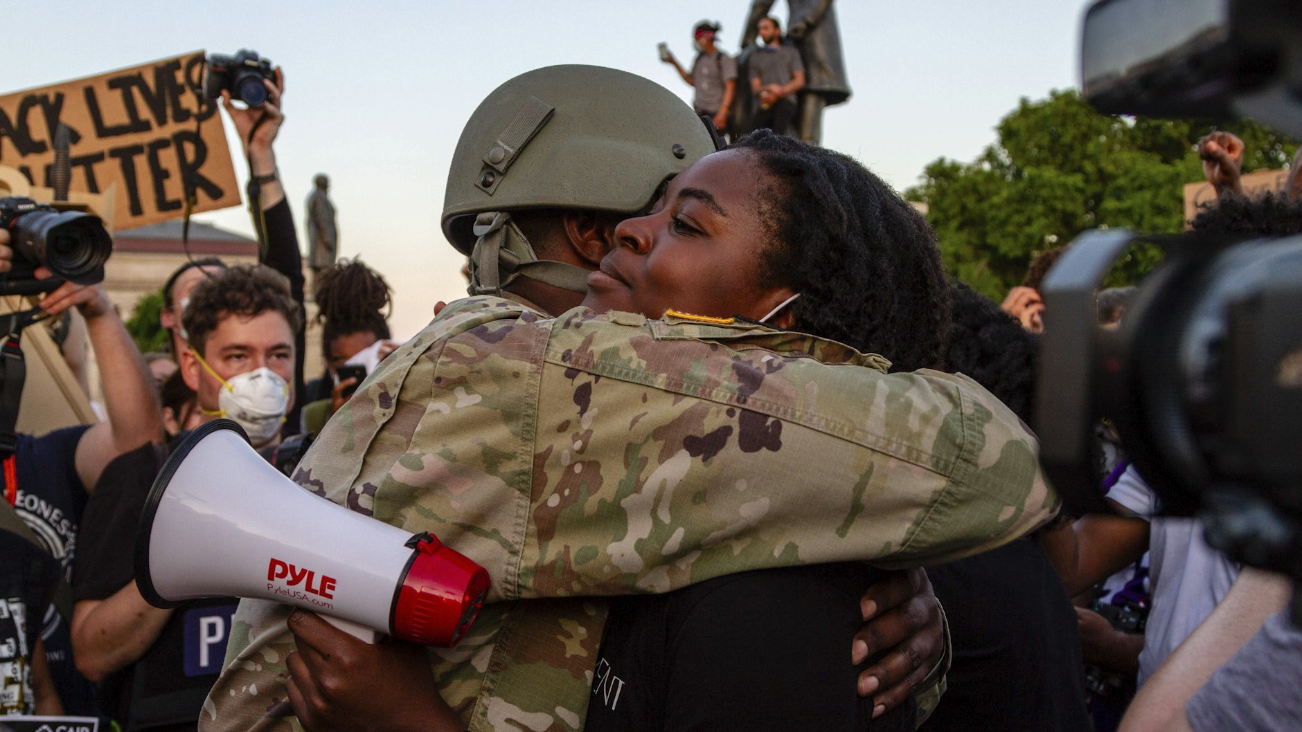 Während Trump die Lage anheizt, versuchen die Menschen, den Zwiespalt zu überwinden. Bei einer friedlichen Kundgebung in Saint Paul (Minnesota) umarmen sich eine Demonstrantin und ein Nationalgardist. 
