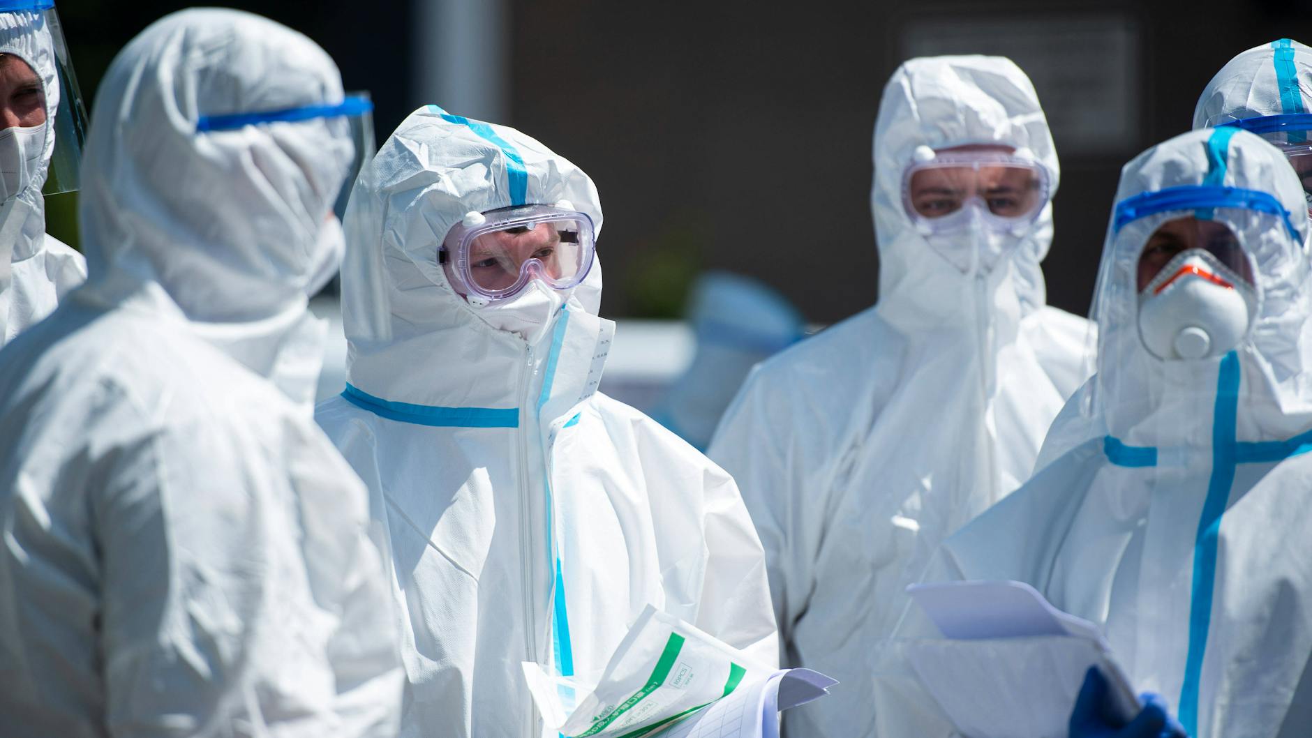 Menschen in Schutzanzügen.