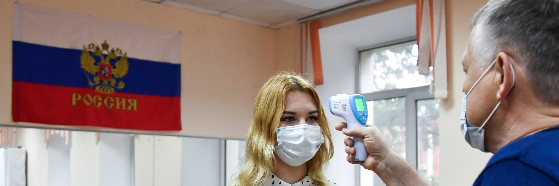 Ein Wahlhelfer misst im fernöstlichen Wladiwostok bei einer Frau Fieber - Vorsichtsmaßnahme wegen Corona. 
