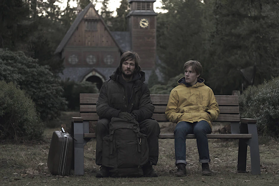 Szene aus „Dark“: Die Schauspieler Andreas Pietschmann und Louis Hofmann sitzen vor der Kirche auf dem Stahnsdorfer Friedhof.
