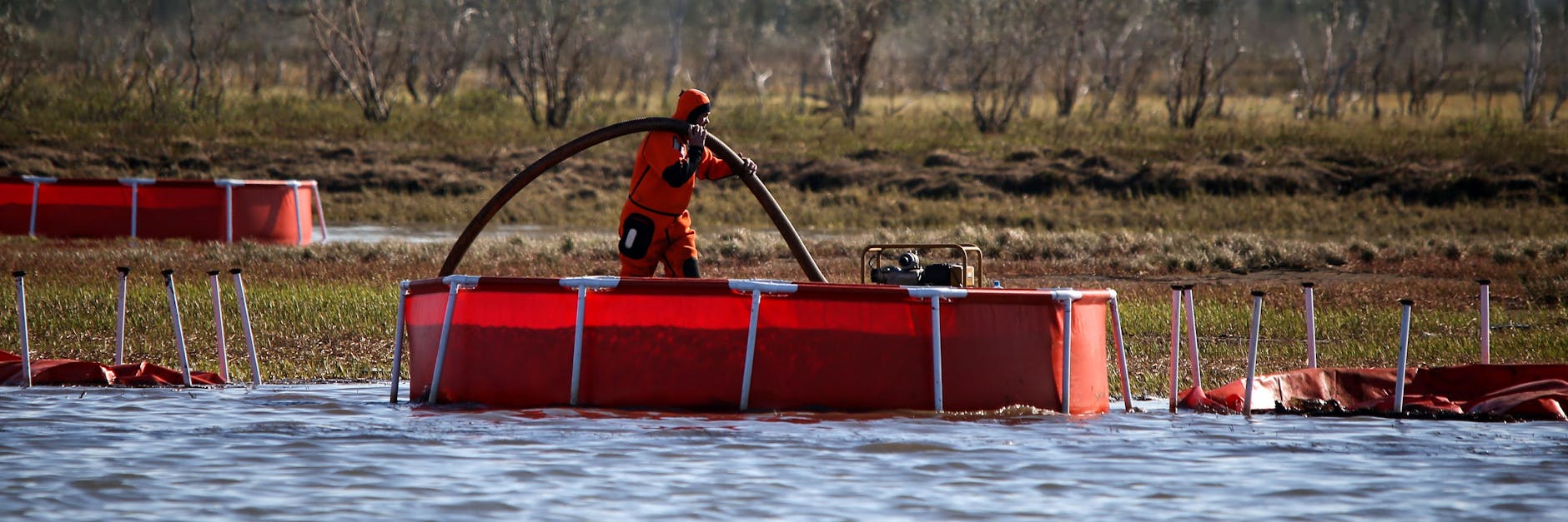 Ein Arbeiter pumpt den Diesel-Kraftstoff von der Wasseroberfläche des Flusses Ambarnaja ab.