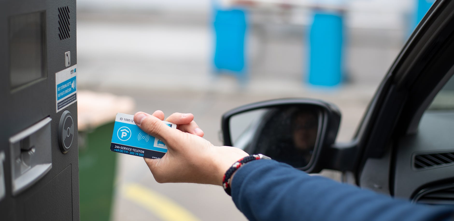 Eine Dauerparkkarte wird an einem Parkplatz an eine Schranke gehalten. 