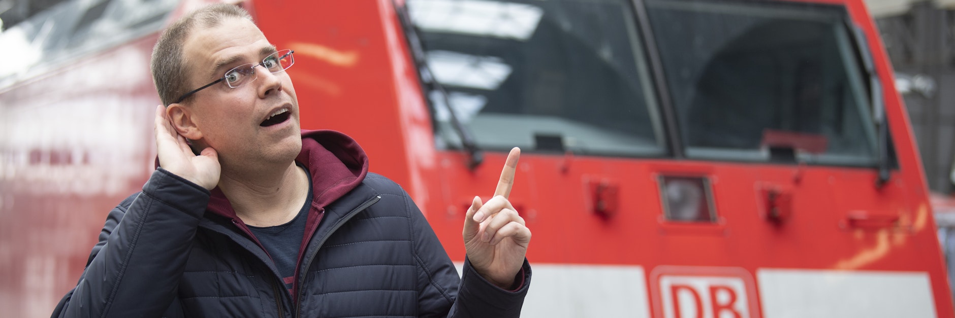 Der neue Bahnansager Heiko Grauel steht auf dem Hauptbahnhof Frankfurt vor einem Zug.
