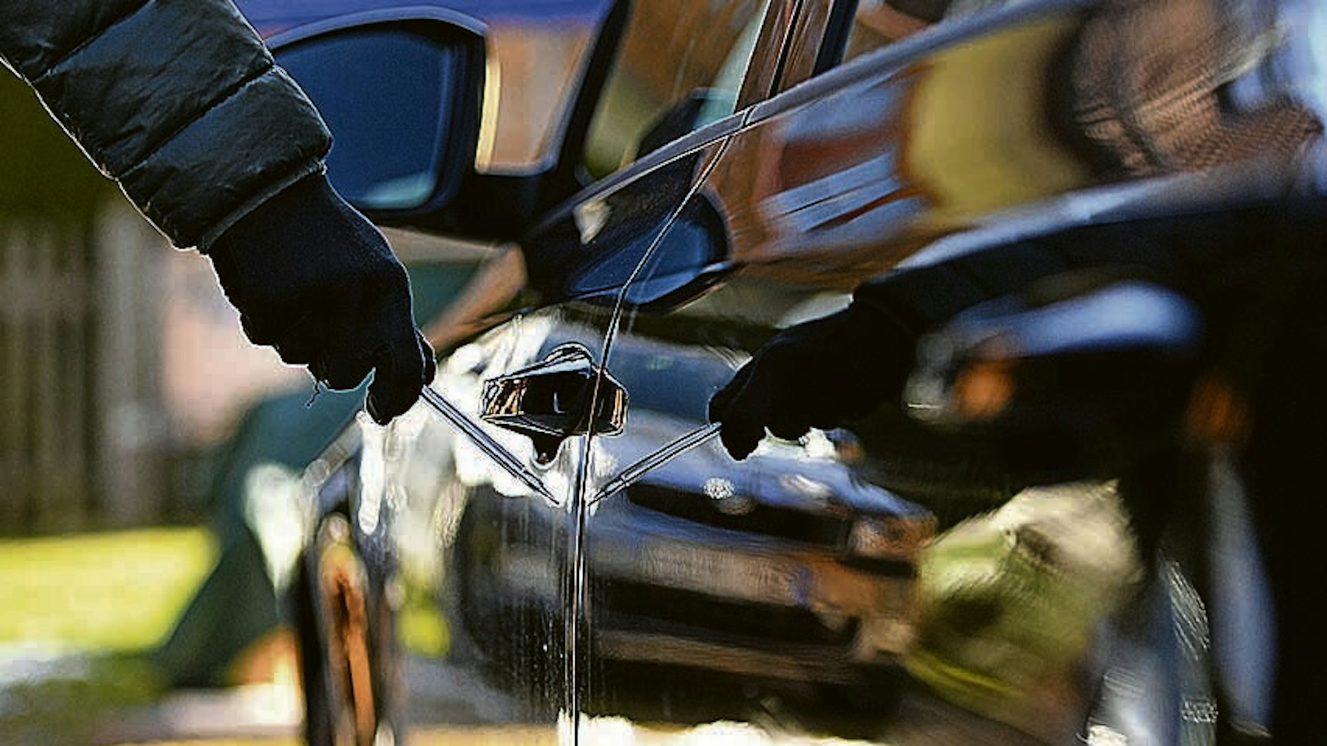 Ein Mann steht mit einem Schraubenzieher neben einem Auto.