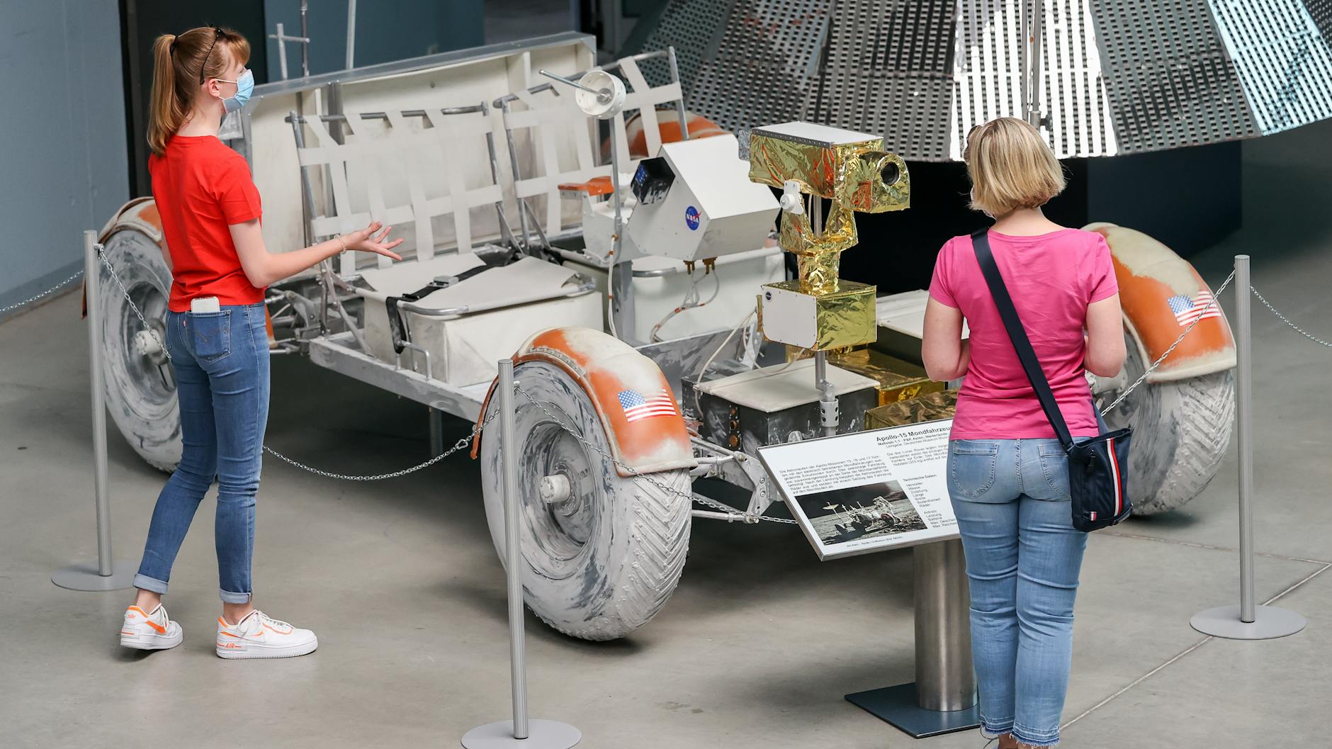 Besucherinnen der Deutschen Raumfahrtausstellung stehen an einem 1:1 Modell des Lunar Rovers der Apollo-15-Mission.