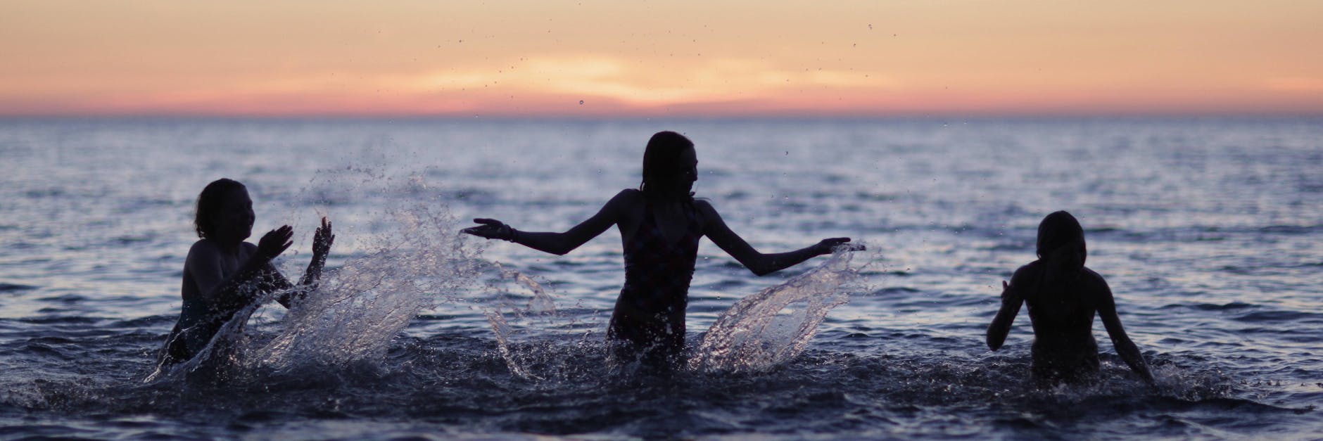 Kinder planschen im Meer.