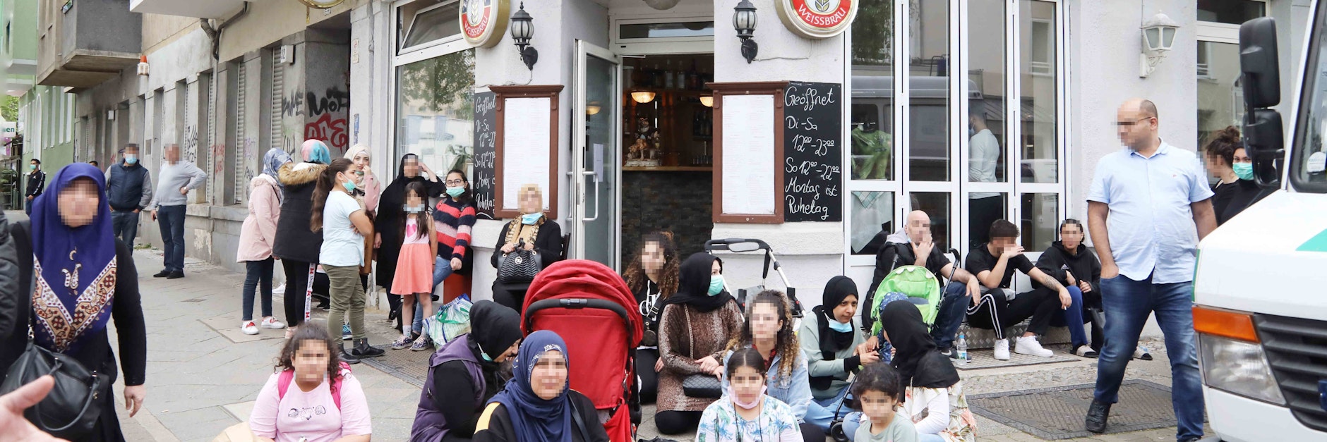 Frauen und Kinder haben sich auf dem Gehweg gegenüber dem Brandhaus niedergelassen. Sie fühlen sich im Stich gelassen.