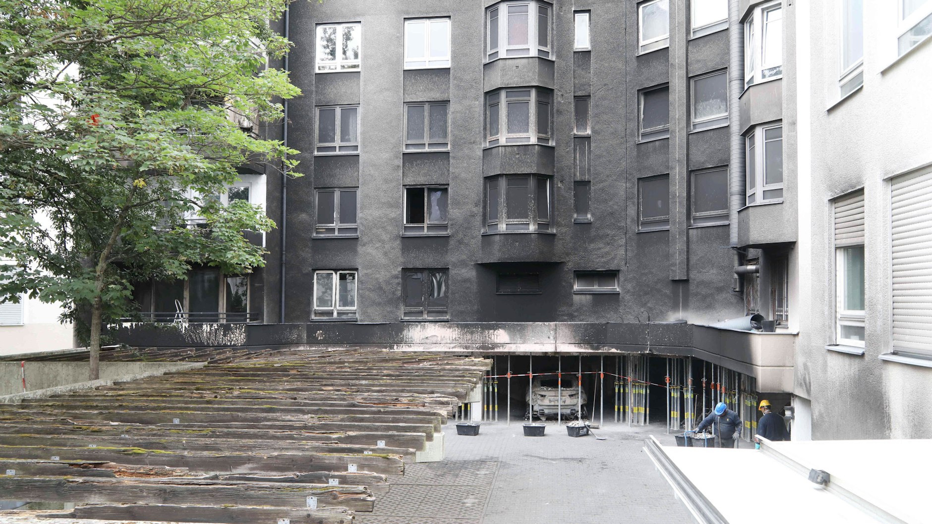 Die Hoffassade ist rußgeschwärzt, Stahlstempel stützen das Haus ab. Ein Autowrack steht noch in der Tiefgarage.