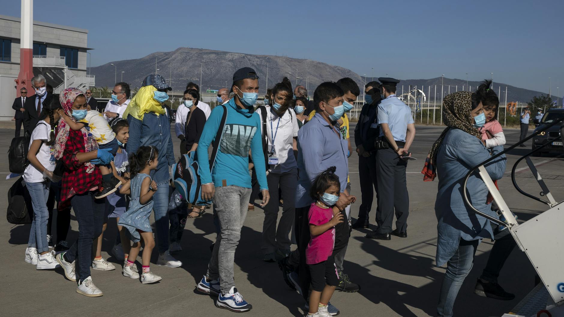 Migrantenkinder mit Gesundheitsproblemen und ihre Angehörigen steigen am Internationalen Flughafen in Athen in eine Maschine zu ihrem Flug nach Deutschland. Am Freitagabend kamen die Familien in Berlin an.