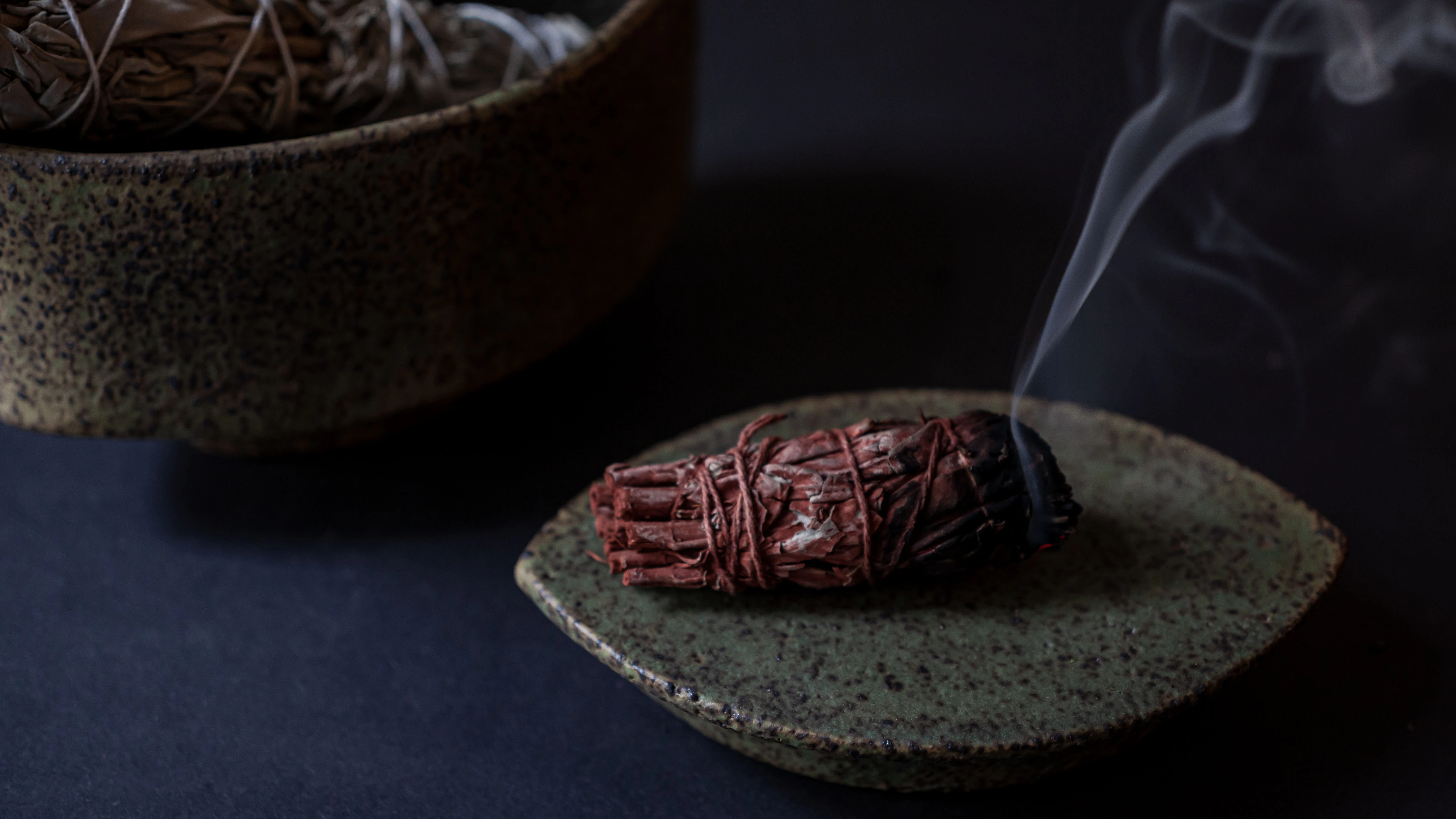 Ein Salbei-Smudge, getaucht in das flüssige, rote Harz des Drachenblutbaums, einer Palmenart aus Südostasien. Nach dem Anzünden entfaltet das Räucherwerk die wohltuende Wirkung beider Pflanzen.