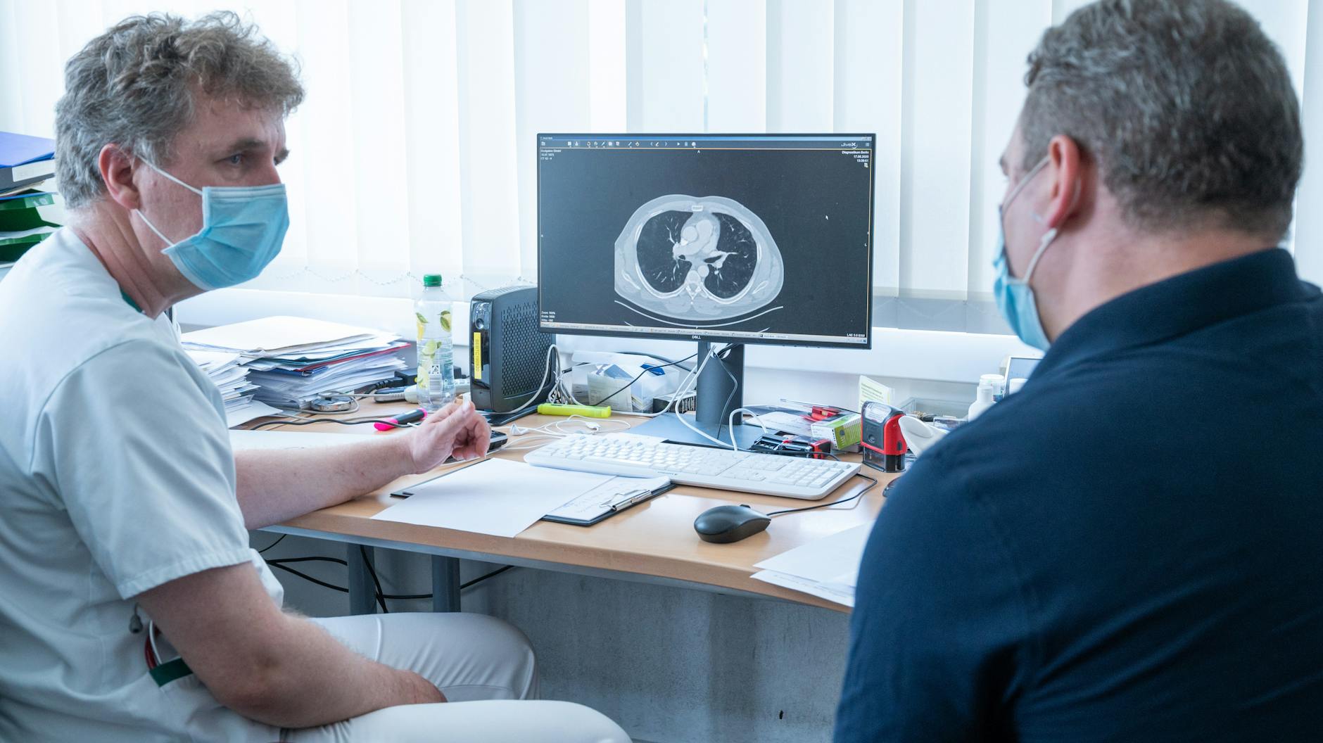 Lungenfacharzt Torsten Blum (l.) zeigt einem Patienten eine Computertomographie seiner Lunge. 