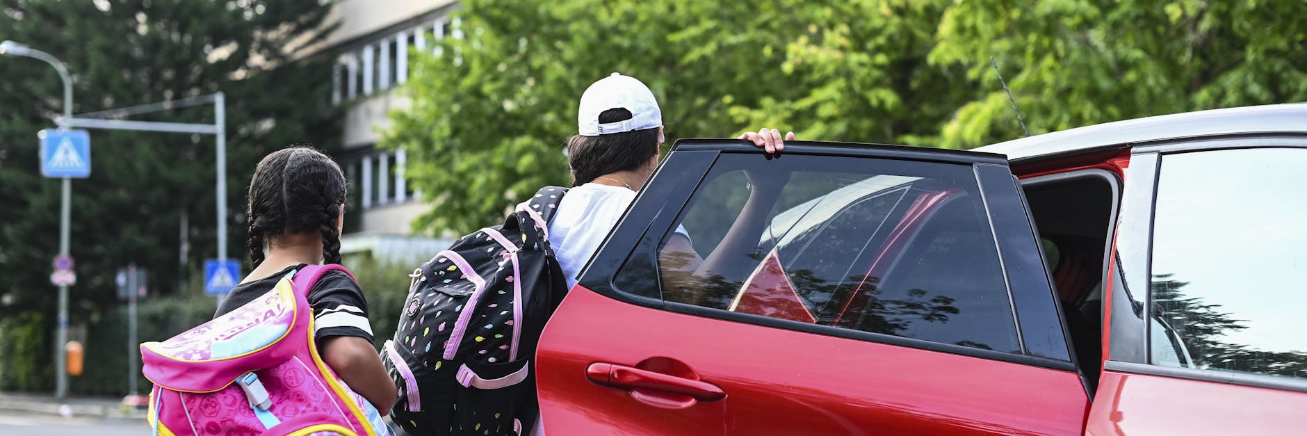 Zwei Mädchen steigen vor der GutsMuths-Grundschule in Mitte aus dem Auto ihrer Eltern aus.