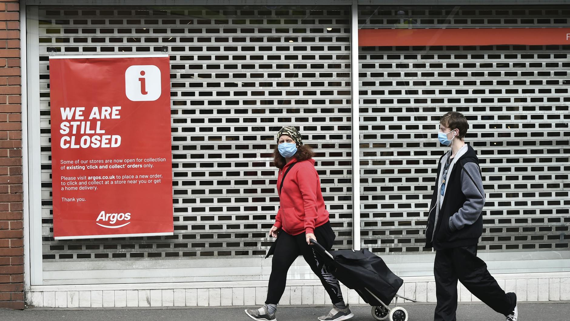 Großbritannien während des Lockdown: Menschen mit Mundschutz gehen an einem geschlossenen Laden im Stadtzentrum von Leicester vorbei.