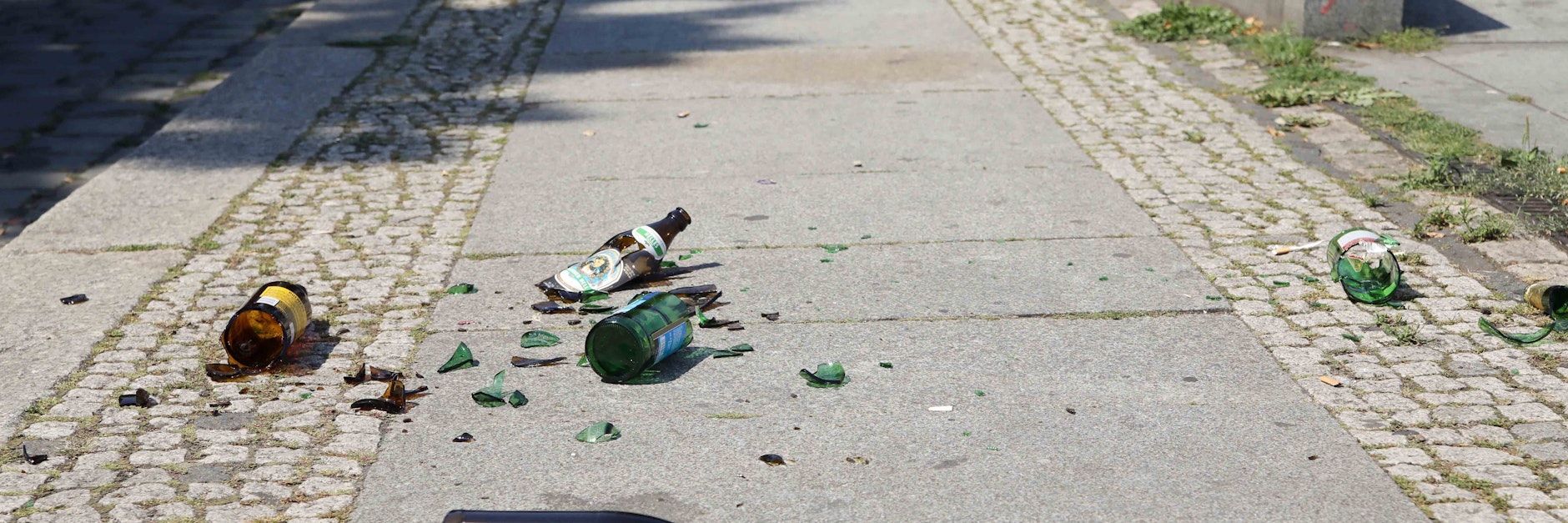 Am May-Ayim-Ufer in Kreuzberg liegen zerbrochene Bierflaschen auf dem Gehweg.
