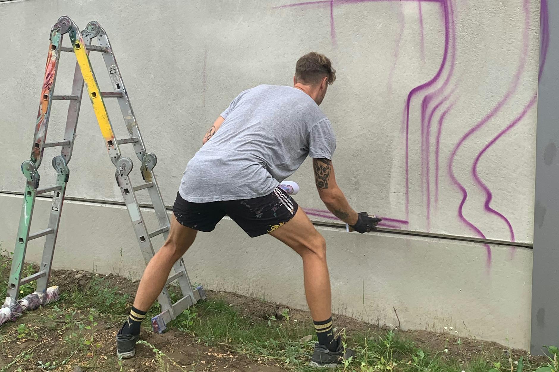 Voller Körpereinsatz: Tom skizziert sein Werk auf der Mauer.
