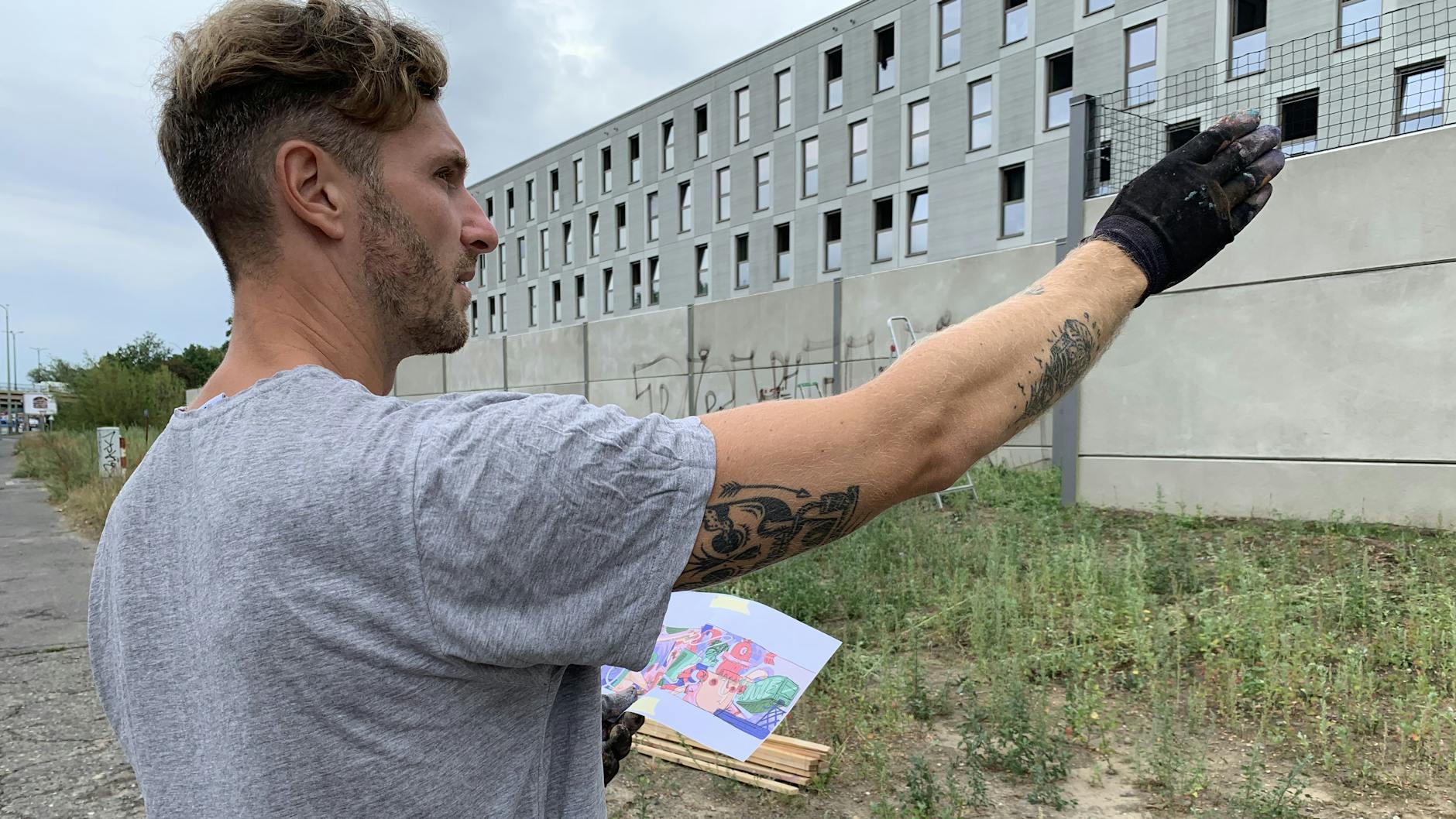 Tom Hrvb teilt die Räume auf der Wand gedanklich ein, hält seinen Entwurf in der Hand.