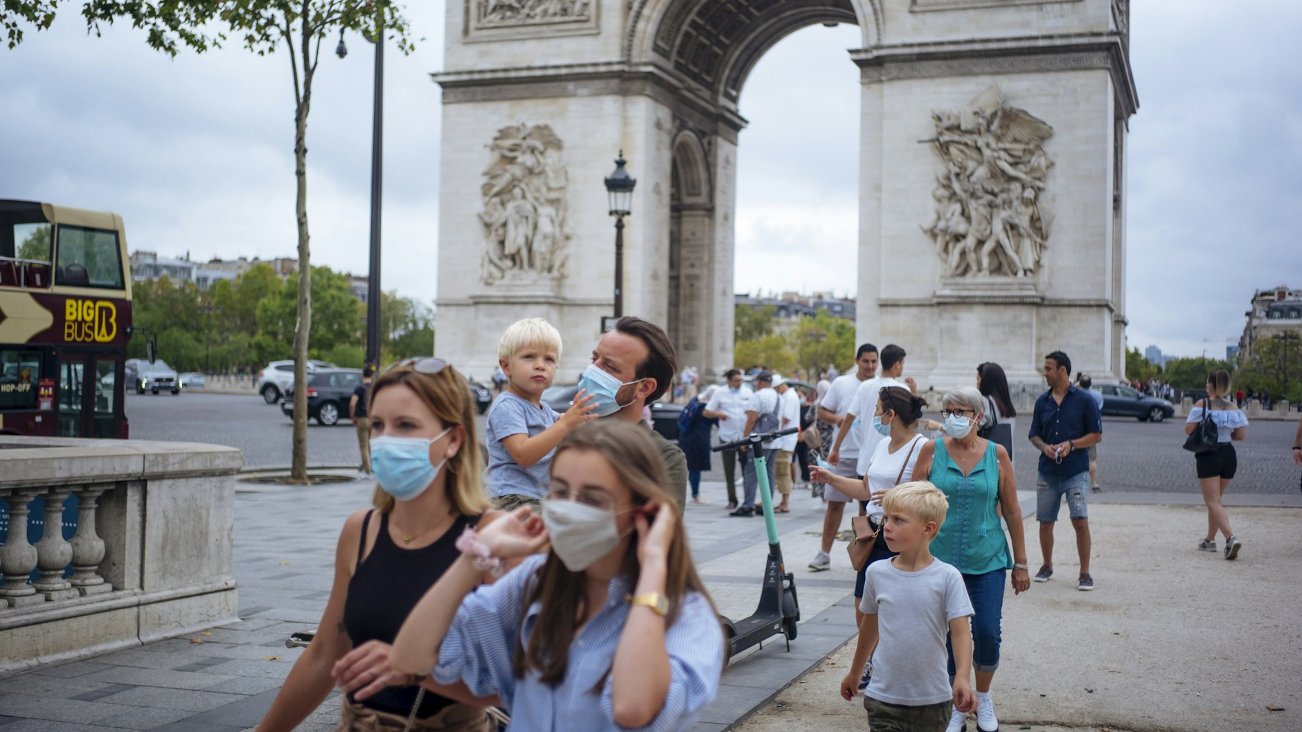 Touristen mit Schutzmasken spazieren auf der Prachtstraße Champs-Elysees.