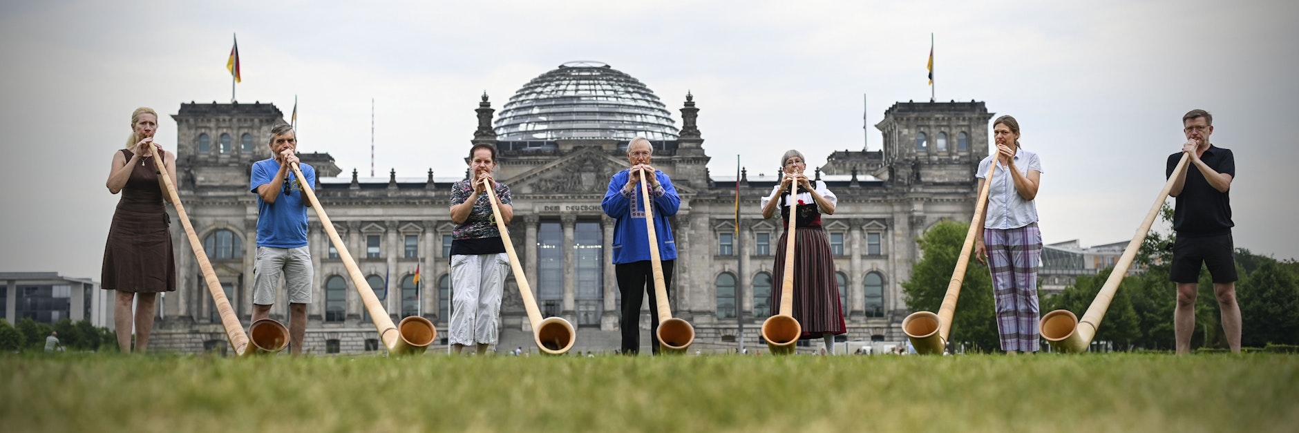 Die Hörner sind ausgepackt, die Probe beginnt: Die Mitglieder des Alphorn-Vereins vor dem Reichstag.