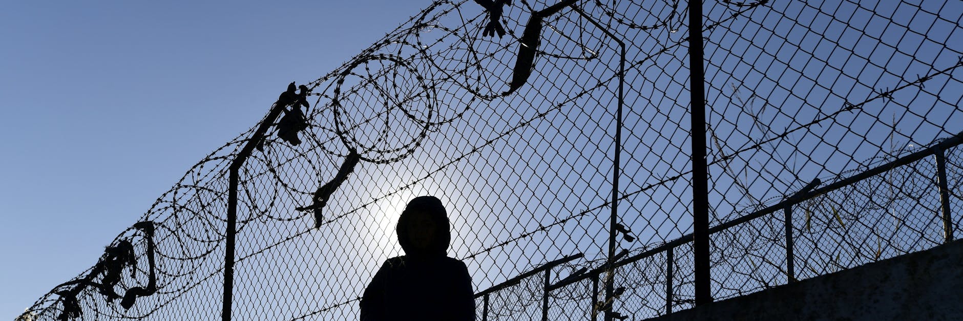 Ein Flüchtling sitzt an einem Zaun des Flüchtlingslagers Moria auf Lesbos.